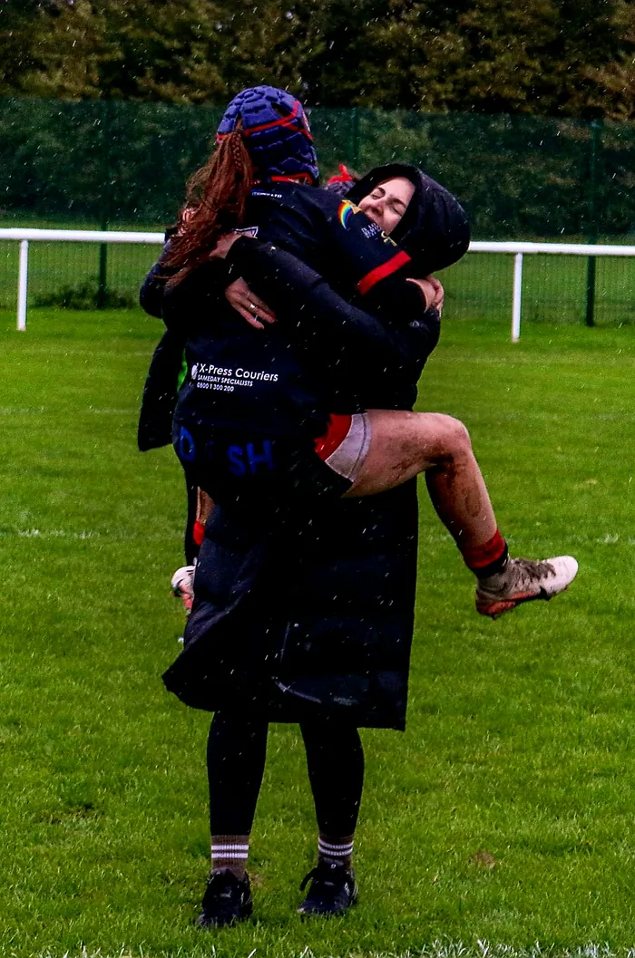 A young Thatto Heath player in X-Press Couriers sponsored kit jumping into her mum's arms to celebrate after a game