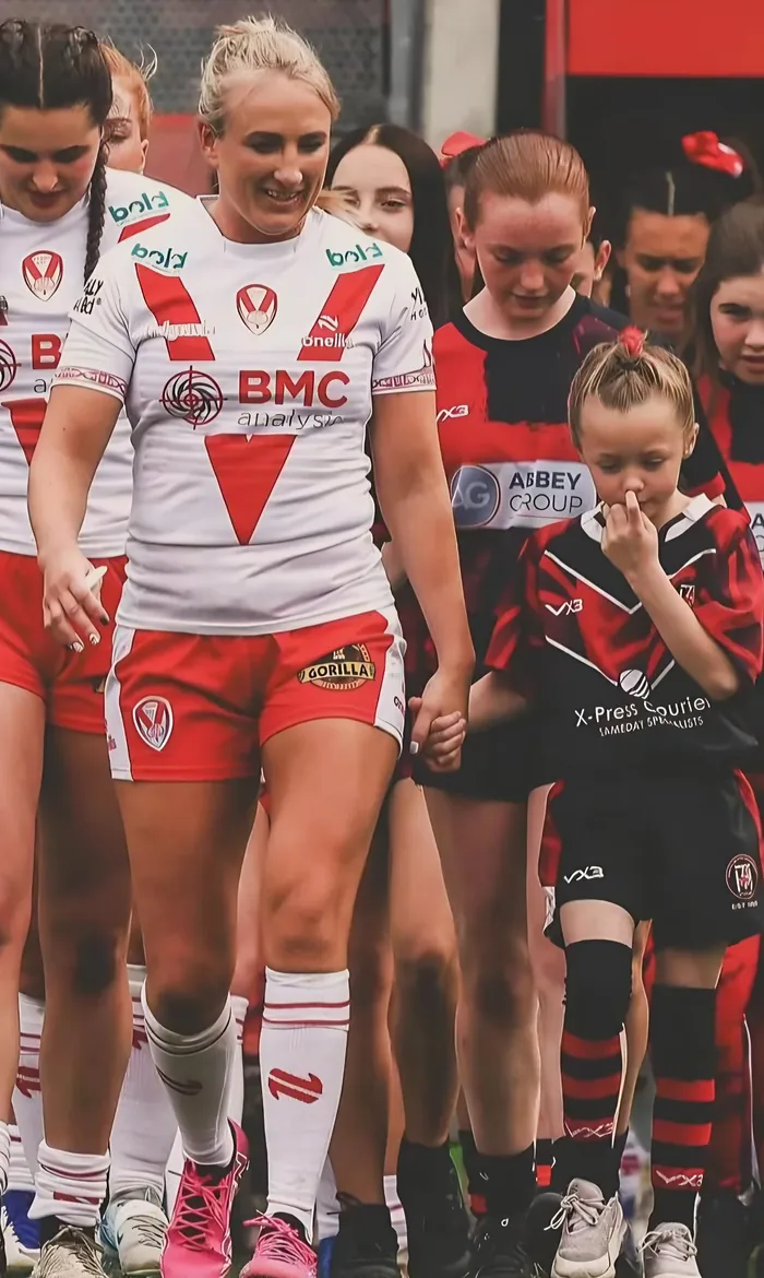A young Thatto Heath player in the X-Press Couriers sponsored shirt walking out hand in hand on a big match day